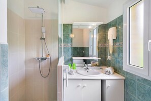 Un baño con ducha, lavamanos y espejo.