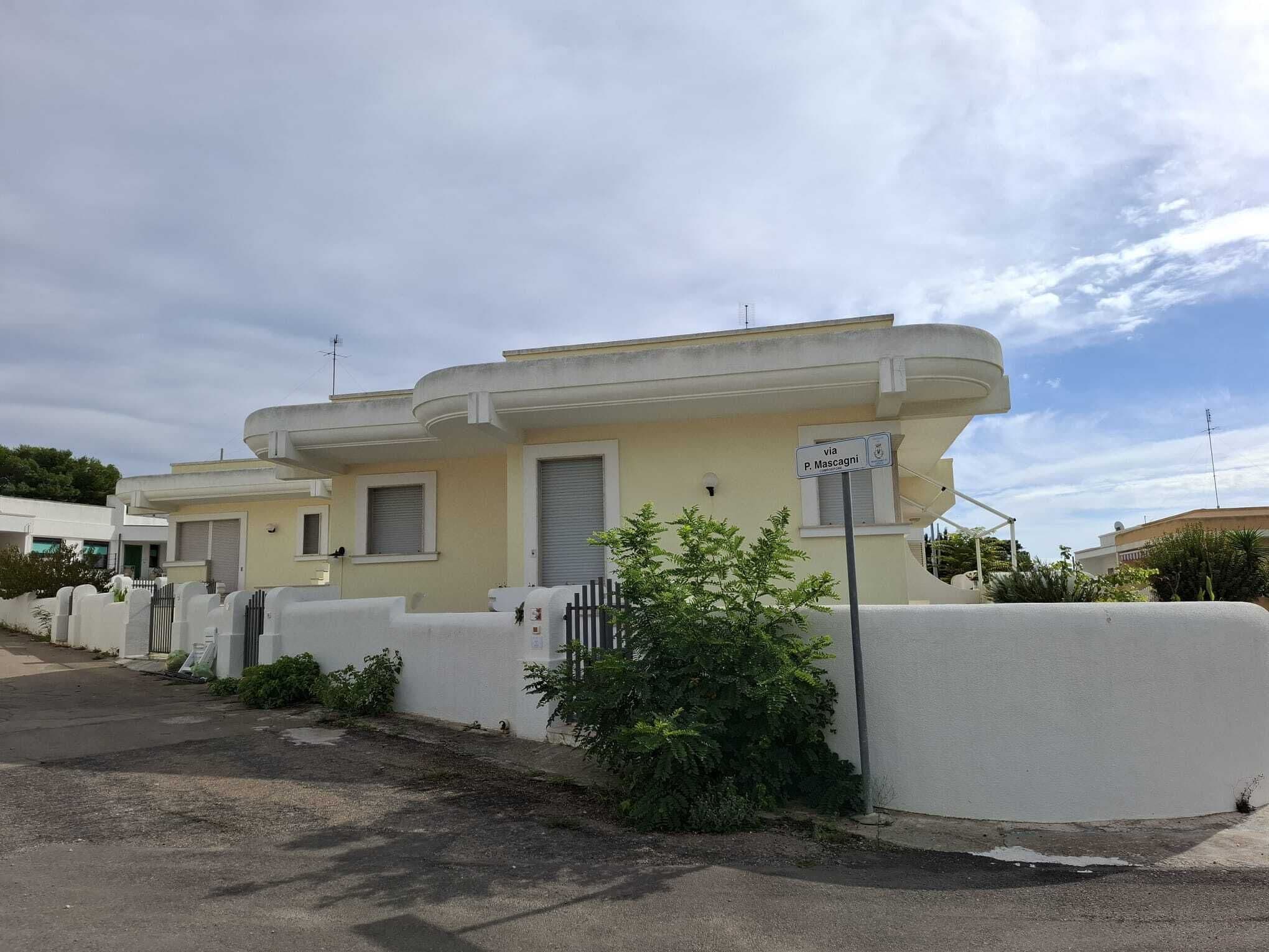 Une rangée de maisons modernes, de plain-pied, avec un toit plat et une façade blanche.