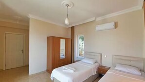 Camera da letto con due letti, un armadio, una ventola a soffitto e un condizionatore d'aria.