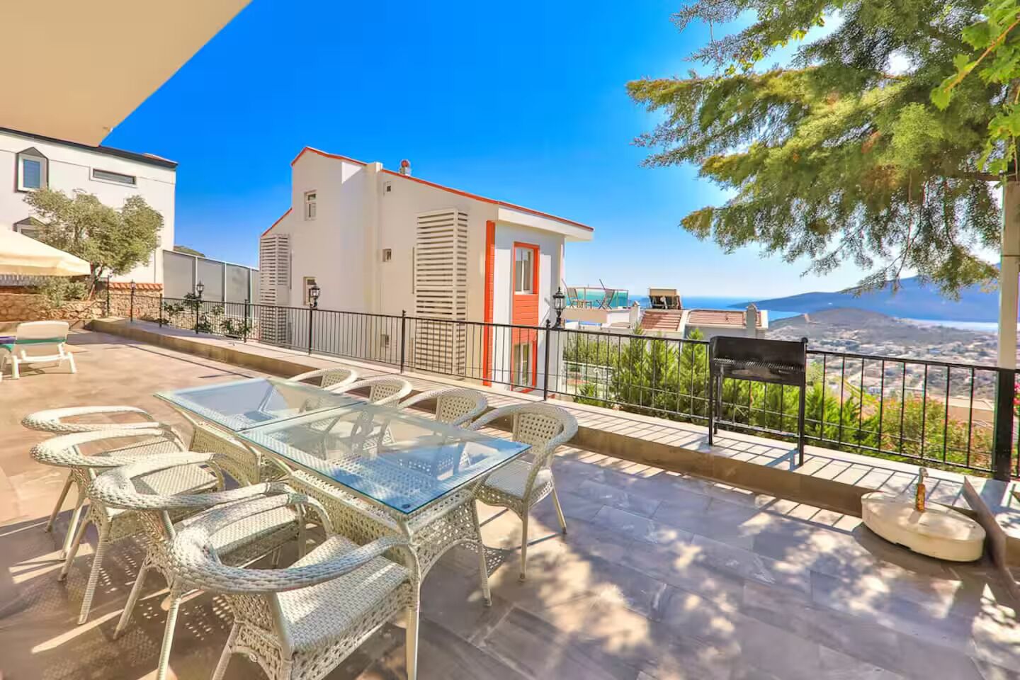 Una terraza con mesa de vidrio y sillas de mimbre, con vista al mar.