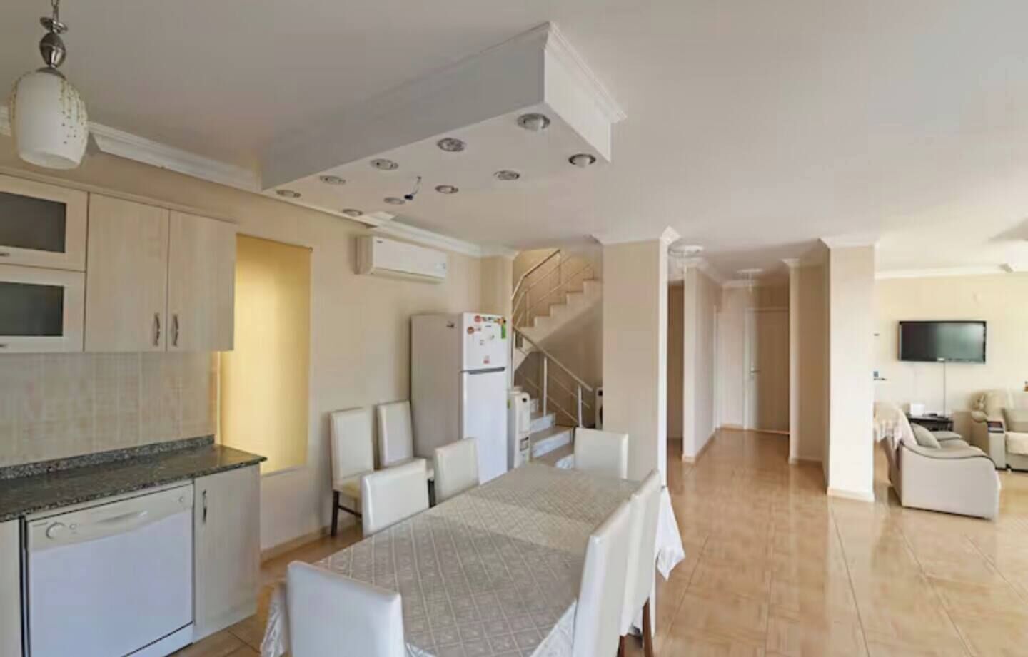 Un appartement moderne comprenant une cuisine, un coin repas, un salon et un escalier menant à l’étage supérieur.