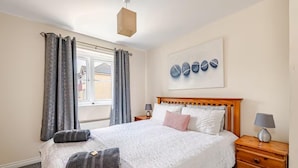 Un dormitorio ordenado con cama, mesitas de noche y ventana con cortinas.