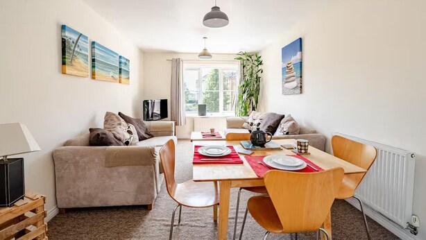 Una sala de estar acogedora con un sofá, una mesa de comedor para dos personas y un televisor sobre un mueble.