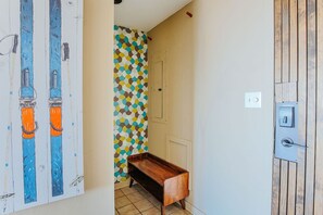 Un couloir étroit avec un banc en bois, une porte et un mur orné d’un motif géométrique.