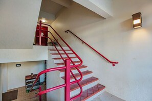 Una escalera con barandillas rojas y una lámpara en la pared.