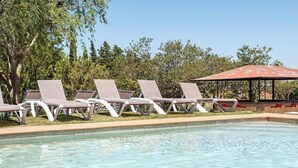 Un área de piscina con sillones de descanso y un pabellón.