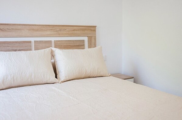 A neatly made bed with a wooden headboard and two pillows.