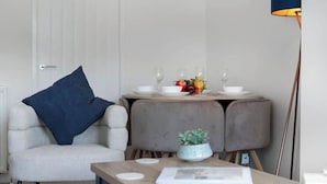 A modern room with a white chair, a table with a blue cushion, a small plant, and a lamp. - Fraser Apartment- 2 Bedrooms Inverleith, Edinburgh (Edinburgh)