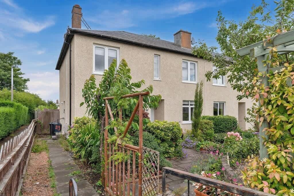A residential building with a garden, a wooden fence, and a metal gate.