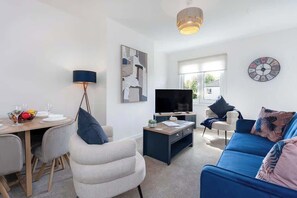 Ein modernes Wohnzimmer mit Fernseher, Sofa und Essbereich.