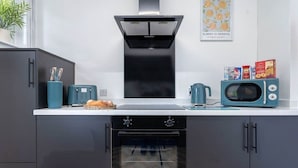A kitchen with a black oven, a microwave, and a toaster. There is a potted plant on the window sill. - Fraser Apartment- 2 Bedrooms Inverleith, Edinburgh (Edinburgh)