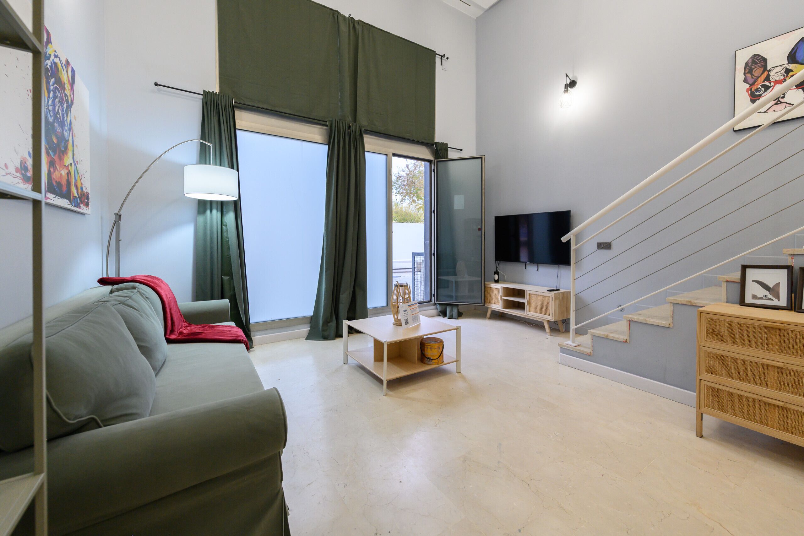 Een moderne woonkamer met een bank, salontafel, televisie en een trap.