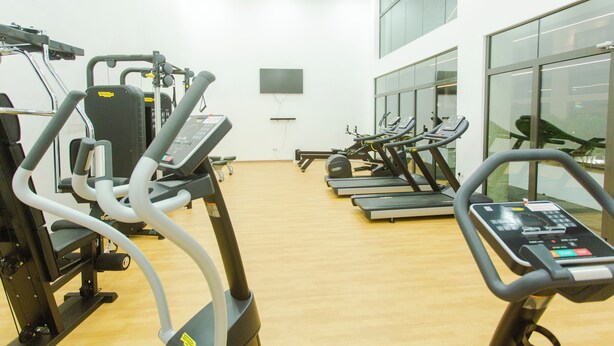 Une salle de sport équipée de plusieurs tapis de course, de vélos d’appartement et d’appareils de musculation.