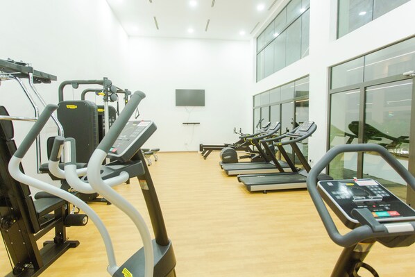 A gym with multiple treadmills, stationary bikes, and weight machines. - Spacious One Bedroom Apartment @ Signature (Accra)