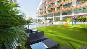 Un bâtiment moderne doté d’une aire de jeux, d’un espace extérieur aménagé pour s’asseoir et d’une pelouse bien entretenue.