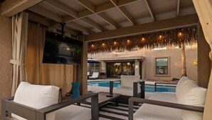 A covered outdoor seating area with white cushioned sofas and a pool in the background. - Scottsdale Luxury Villa w/ Pool, Hot Tub, Pickleball, Mini-Golf, Basketball (Scottsdale)