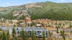 A modern building complex with multiple floors, surrounded by dense forest and hills. - Eagle River Retreat I Hot tub & Pool (Avon)