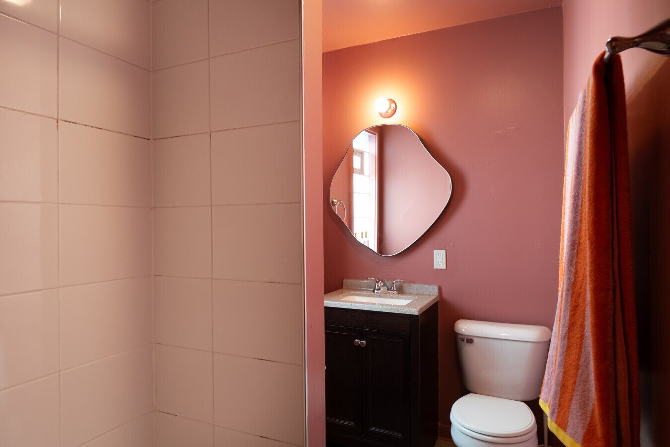 A bathroom with a toilet, sink, and mirror.