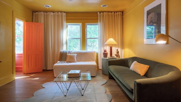 A room with a sofa, a glass coffee table, a lamp, and a door. - Entire Designer Building, Sleeps 13 (Milwaukee)