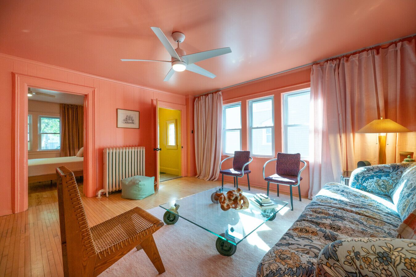 Une pièce comprenant un lit, deux chaises, une table, un ventilateur de plafond et une fenêtre.