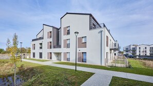 Een modern, meerlaags woongebouw met een plat dak, grote ramen en een centrale binnenplaats.