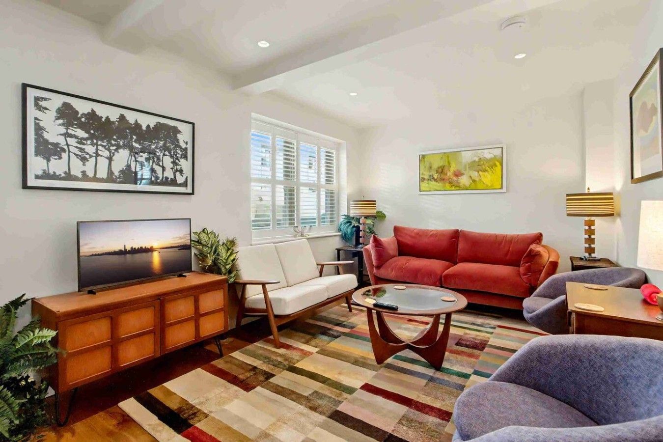 A living room with a television, sofa, armchair, coffee table, and a patterned rug.