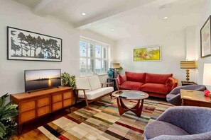A living room with a television, sofa, armchair, coffee table, and a patterned rug. - Ruston Mews – Notting Hill Hideaway (London)