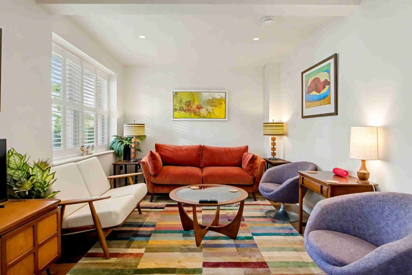 Una sala de estar con sofá, sillones, una mesa de centro y televisor.