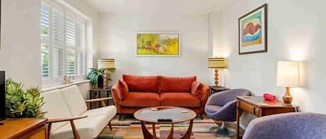 Una sala de estar con sofá, sillones, una mesa de centro y televisor.