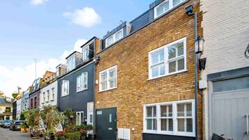 A row of terraced houses with brick facades, white window frames, and a clear sky.
