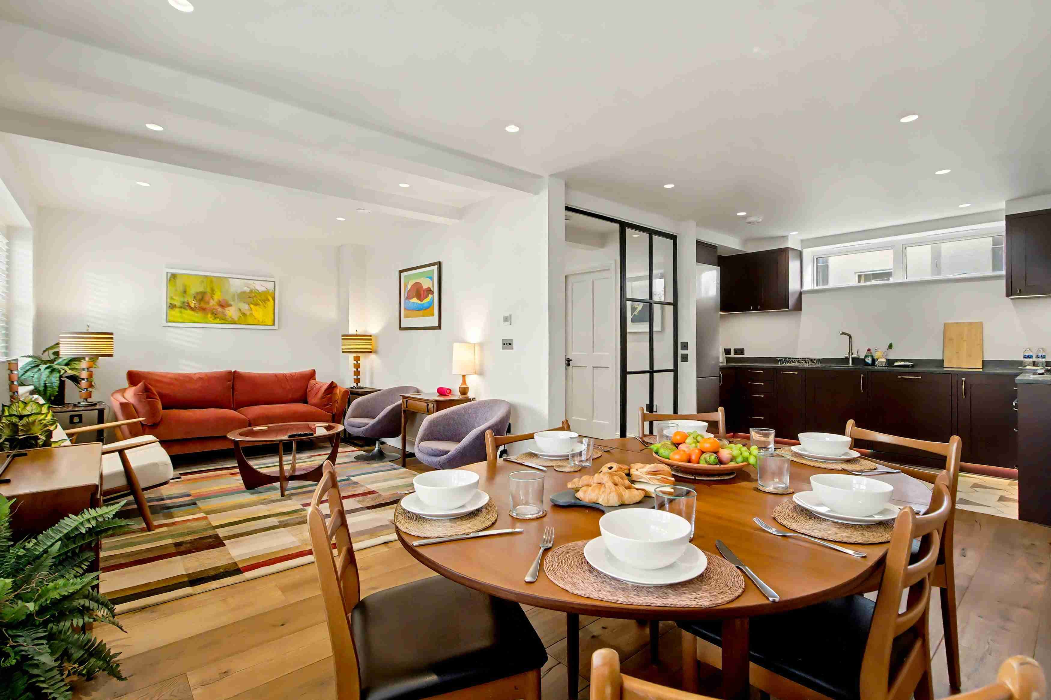A modern living room with a sofa, chairs, and a dining table set for a meal.
