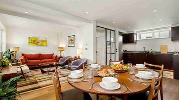 A modern living room with a sofa, chairs, and a dining table set for a meal.