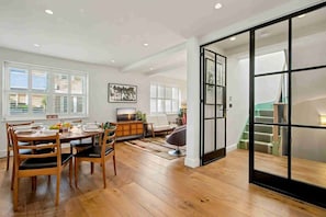 A dining area with a wooden table and chairs, a television, and a cabinet. - Ruston Mews – Notting Hill Hideaway (London)