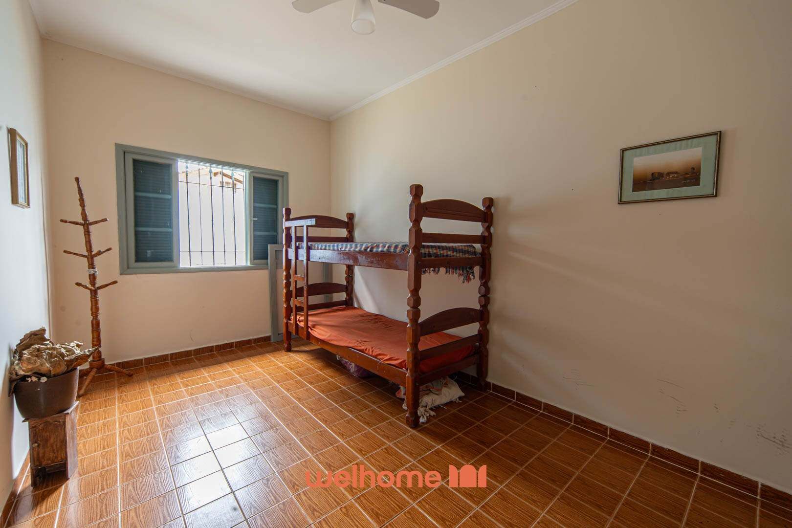 A room with a bunk bed, a window with blinds, a ceiling fan, and a framed picture on the wall.