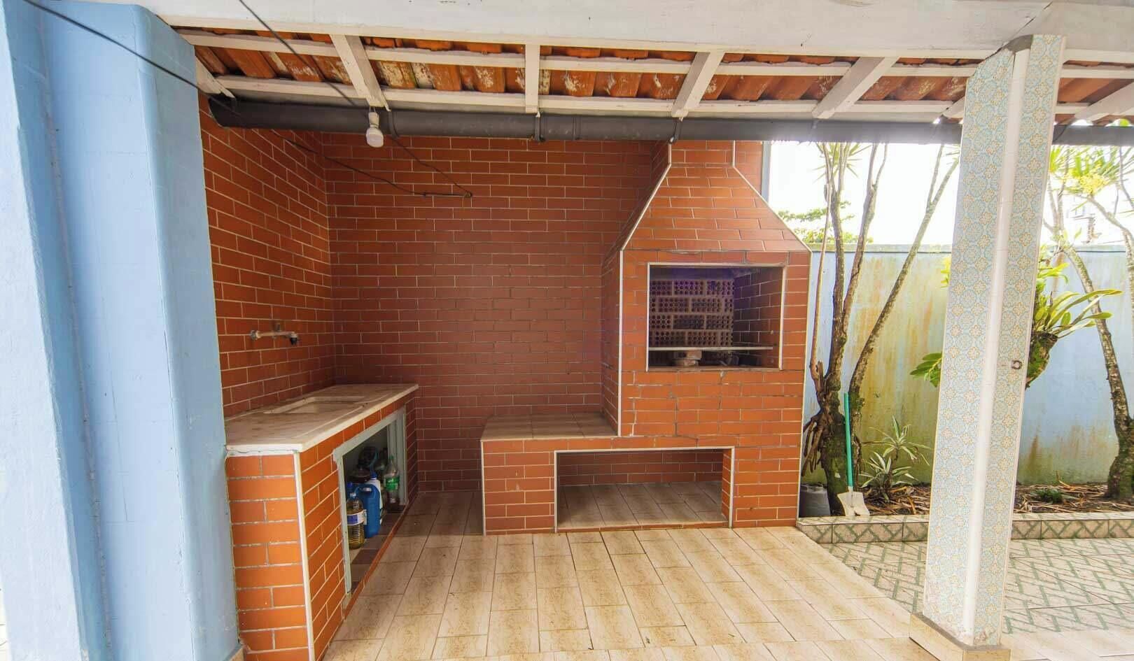 A brick-built outdoor kitchen area with a chimney, a built-in sink, and a shelf for storage.