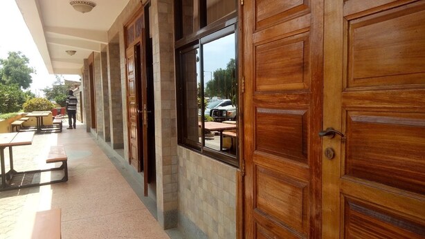 A covered outdoor area with wooden doors and windows, a tiled floor, and outdoor seating. - Northern Galaxy Hotel Isiolo (Isiolo)