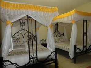 A room with two four-poster beds, each with a canopy and yellow accents. - Northern Galaxy Hotel Isiolo (Isiolo)