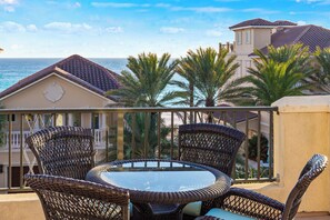 A balcony with wicker furniture and a glass table overlooking the ocean. - Pet Friendly | Walk to Beach | Gulf Views | Destin Beach House | Sleeps 15 (Destin)