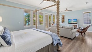 Quarto com cama de dossel, sofá, televisão e ventoinha no teto.