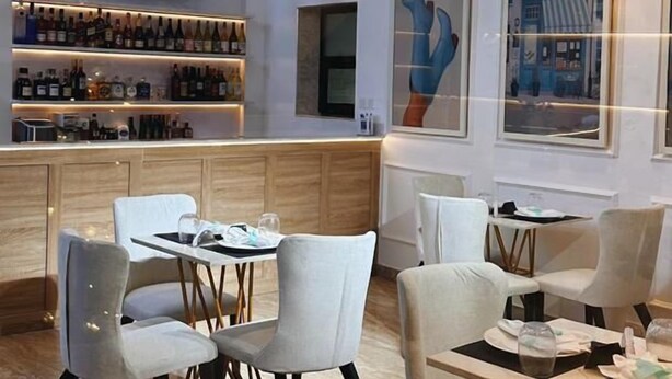 A modern restaurant interior with a bar area, dining tables, and hanging pendant lights. - Mayhill Signature (Lekki)