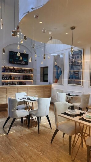A modern restaurant interior with a bar area, dining tables, and hanging pendant lights. - Mayhill Signature (Lekki)