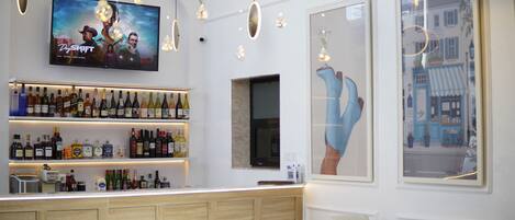 A bar area with a television displaying a Netflix show, shelves of liquor, and a large window with a city view.