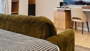 A modern bedroom with a bed, a desk, a TV, and built-in shelving. - Mayhill Signature (Lekki)