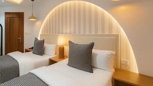 A hotel room with two beds, a curved wall design, and modern lighting fixtures. - Mayhill Signature (Lekki)