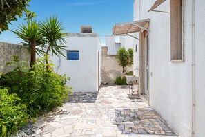 A narrow courtyard with a tiled floor, a small table, and a door. - Bonavista Holiday Villa with Sea View, Wi-Fi and Air Conditioning (Torre Lapillo)