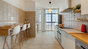 A kitchen with a bar area, a washing machine, and a red kettle.