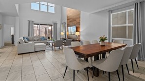 Een ruime woonkamer met een eettafel, banken en een keuken op de achtergrond.
