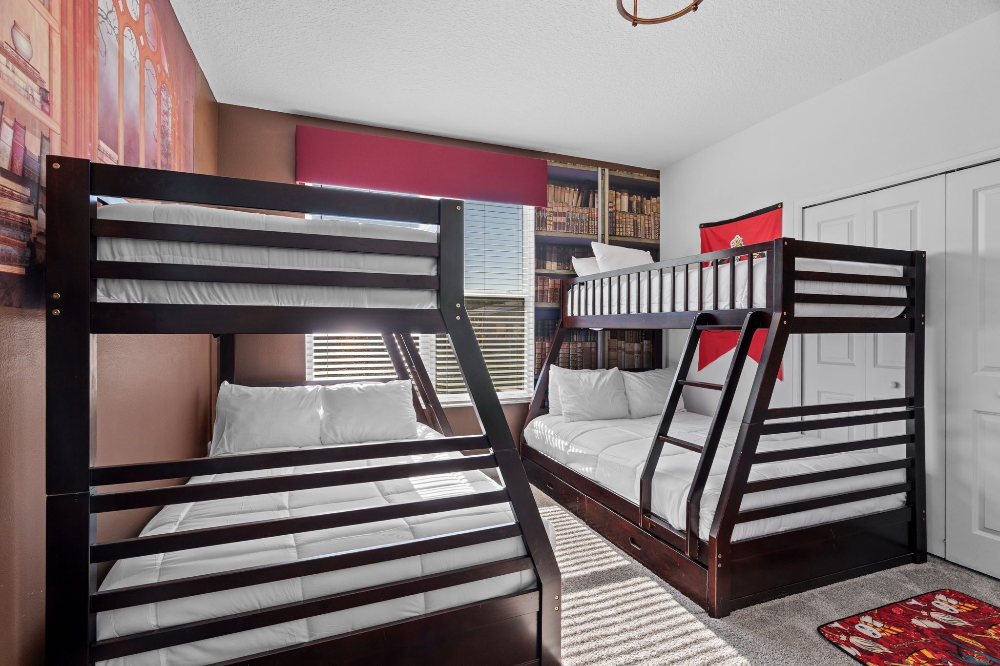 A room with two bunk beds, a bookshelf, and a door.