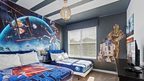 Een slaapkamer in Star Wars-thema met een muurschildering, twee bedden, een bureau en een Star Wars-beeldje.