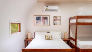 A bedroom with a wooden bed, a nightstand, a bedside table, and a bunk bed. - Siquijor Summit Resort (Lazi)